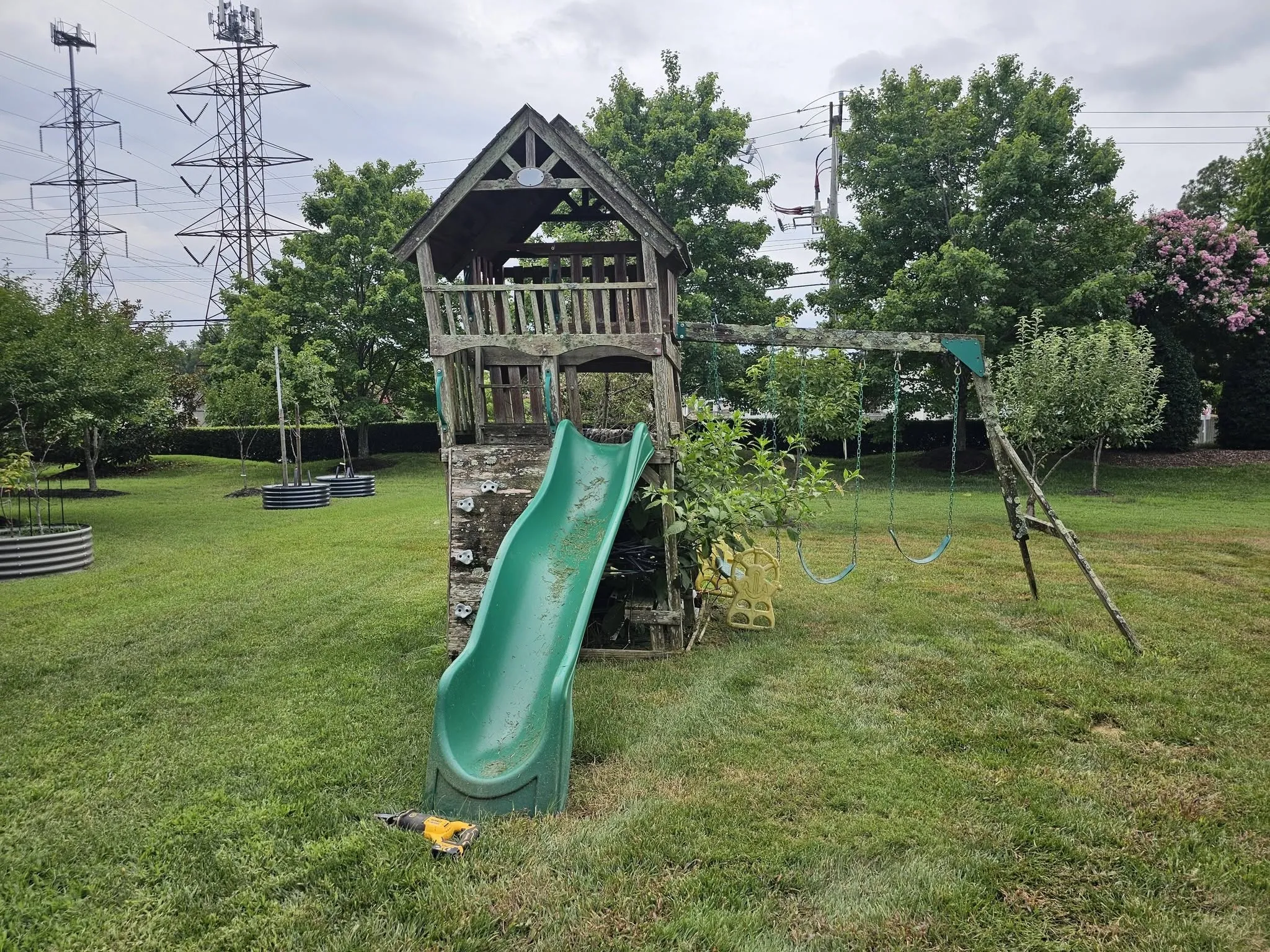 Wooden playset with slide and swing arm on an open lawn